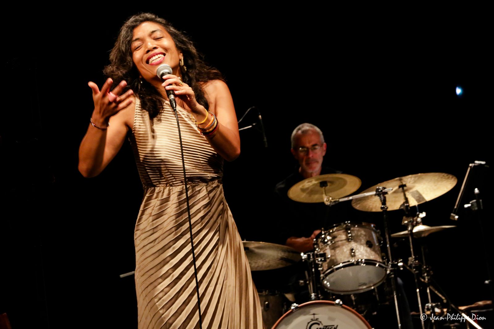 Jinja Andrianambinina-Teyssier chantant sur scène, le batteur derrière elle