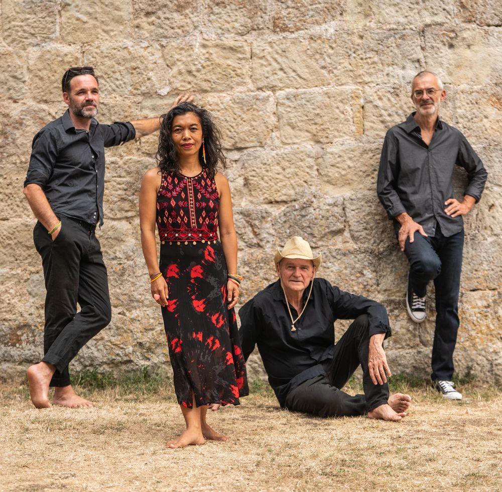 Les quatre musiciens du quartet JINJA devant un mur de pierre
